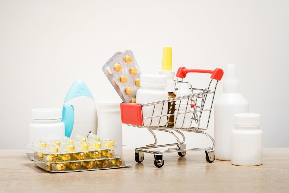 Various capsules, tablets and medicine in shop trolley on a beige background.