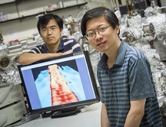 aoyi Li (foreground) and Mingxing Chen, UWM physics postdoctoral researchers, display an image of a ribbon of graphene 1 nanometer wide. In the image, achieved with a scanning-tunneling microscope, atoms are visible as “bumps.”