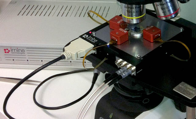 Imina Technologies portable platform with three miBot manipulators operated under an optical microscope to carry out tests on electronic devices.