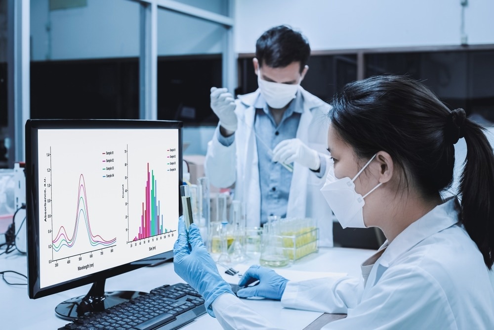 Scientist woman checked the analysis of UV, and nanoparticle size of the sample as shown on a monitor. Blurred background, scientist man experiment with the formulation of nanoparticles of the sample.
