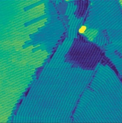 Topography image of hexacontane (C60H122) deposited on highly oriented pyrolytic graphite (HOPG). The image was taken in TappingMode under ambient conditions. Several monomolecular layers of hexacontane are observed. The hexacontane molecules form visible lamellar stripes within each layer. Scan size: 400 nm × 400 nm, height range: 1.04 nm.