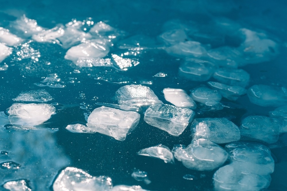 El agua fría y los cubitos de hielo se derriten bajo el fondo del sol.